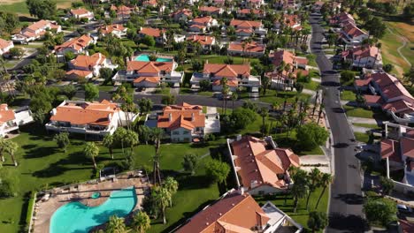 Aerial-high-angle-overview-above-Palm-Springs-California-USA-neighborhood-with-orange-roof-townhomes-and-pool-in-middle-of-community