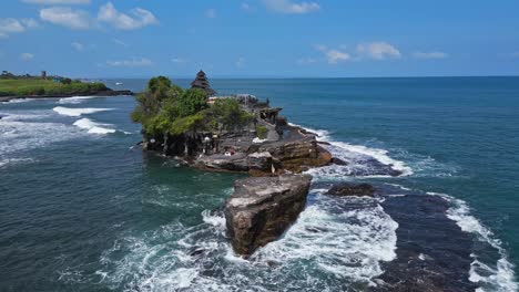 -Las-Olas-Rompen-Y-Bailan-Alrededor-De-Su-Base-Escarpada,-Tanah-Lot,-Paralaje-Aéreo