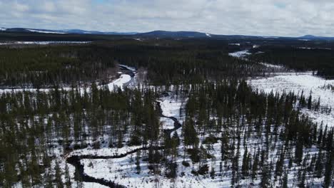 River-Through-Snow-covered-Forest-In-Winter-In-Swedish-Lapland,-Sweden