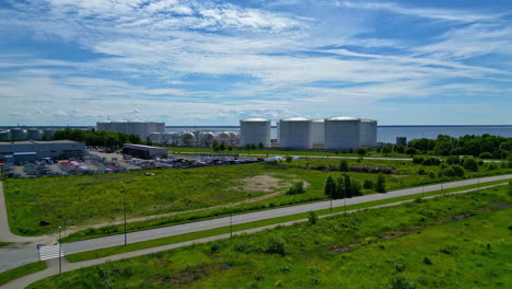 Forward-moving-drone-view-of-an-industry-with-beautiful-landscape-at-background-during-afternoon