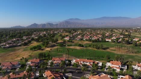 Golf-course-community-with-bright-green-fairways-in-Palm-Springs-California-USA,-aerial-establish