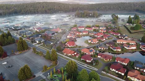 4K-Aerial-view-of-a-a-Swiss-style-village-with-a-lake-and-early-morning-fog-in-Australia