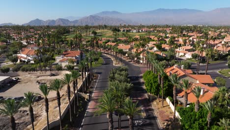 Dolly-Aéreo-Sobre-La-Bandera-Americana-En-El-Asta-De-La-Bandera-En-Palm-Springs,-California,-EE.UU.-Barrio-Con-Carreteras-Pavimentadas-Frescas