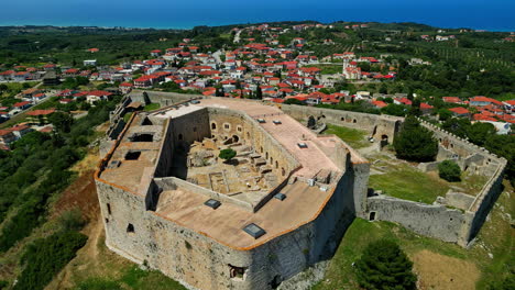 Museo-Del-Castillo-De-Chlemoutsi-Rodeado-Por-Un-Pueblo-Y-Un-Exuberante-Paisaje-Verde,-Vista-Aérea