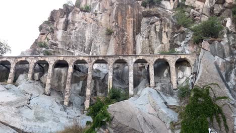 Tilt-up-in-slow-motion-of-a-woman-standing-by-a-fountain-up-towards-the-aqueducts-and-rocks-of-Bunardzhik