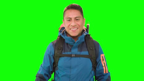 An-adult-man-with-a-backpack,-standing-in-a-studio-with-green-screen,-takes-pictures-with-a-camera