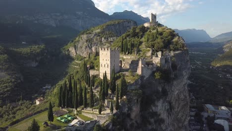 Beautiful-aerial-shot-of-a-stone-tower-on-top-of-a-rock-formation-in-Italy-Dolomites,-Castello-di-Arco,-Riva-del-Garda