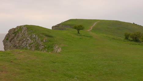 Walking-along-the-cliff-top-path-of-Brean-Down,-England,-overlooking-the-vast-expanse-of-the-sea-and-green-vegetation