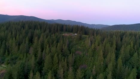 Slow-aerial-zoom-out-from-a-undeveloped-campsite-on-the-side-of-a-evergreen-covered-ridge