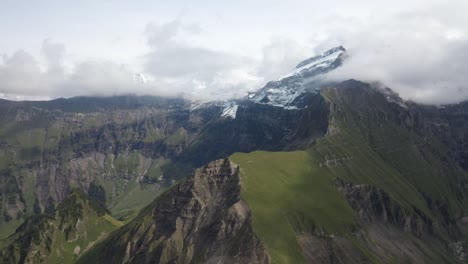 A-pan-up-drone-shot-over-Morgenberghorn-mountain-in-Switzerland-and-the-steep-ridge-extending-far-into-the-distance-to-join-with-snow-covered-mountain-tops