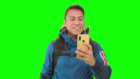 An-adult-male,-with-hiking-backpack-and-yellow-smartphone-in-hand-with-green-screen,-giving-the-impression-that-he-is-texting-