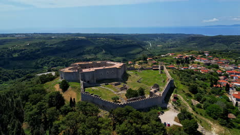 Chlemoutsi-castle-in-greece-on-a-sunny-day-surrounded-by-lush-greenery-and-distant-sea,-aerial-view