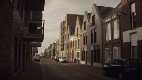 Old-Ijmuiden---Netherland---January-21st-2019-:-still-view-of-classical-vintage-buildings-in-dutch-neighborhood-with-man-riding-bicycle-during-winter