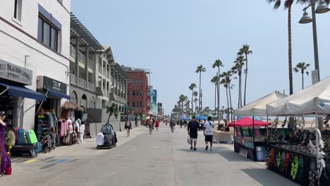 Paseo-Por-La-Playa-De-Venecia-En-Los-ángeles,-California,-Lugar-De-Viaje-Turístico-Durante-La-Variante-Delta-Pandémica-De-Covid-19-En-2021,-Mientras-Que-Los-Peatones-Y-Las-Personas-Que-Viajan-Usan-Máscaras-Mientras-Caminan