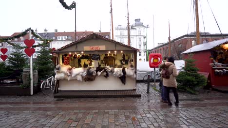 Outdoor-temporary-artist-tents-selling-animal-skins-on-cobblestone-sidewalk-in-downtown-Copenhagen,-Denmark,-slow-motion