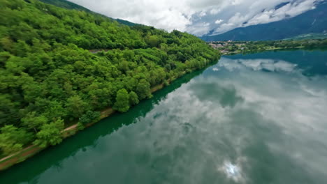 Lago-di-levico-with-lush-green-hills-and-a-peaceful-sky-reflection,-aerial-view