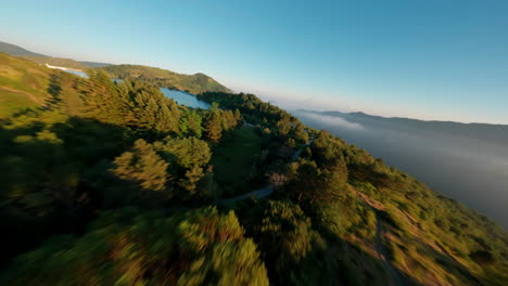 Aerial-view-of-Lake-Giacopiane,-Italy,-with-lush-green-hills-and-morning-mist