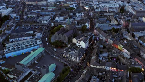 Inclinación-Aérea-Desde-El-Centro-De-La-Ciudad-De-Galway-Hasta-El-Horizonte,-Mostrando-La-Vibrante-Ciudad-Por-La-Noche-Durante-El-Desfile-De-Pegaso