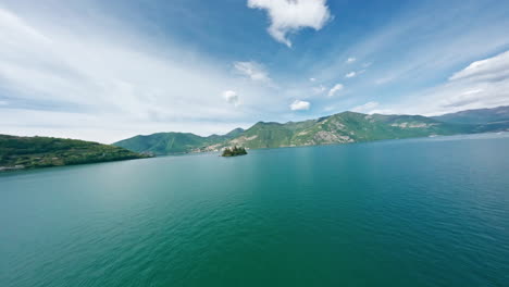 Loreto's-island-in-lago-d'iseo-with-beautiful-mountain-backdrop-and-clear-skies,-aerial-view