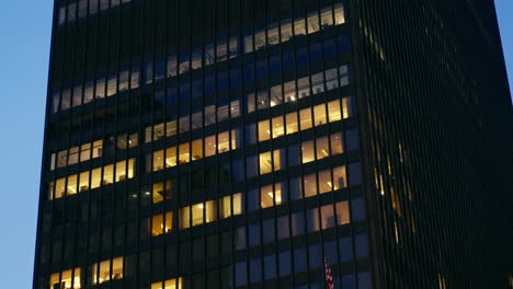 Edificio-De-Oficinas-Por-La-Noche-Con-Varias-Ventanas-Iluminadas-En-Amarillo-Con-Personas-Y-Empleados-Trabajando-Hasta-Tarde