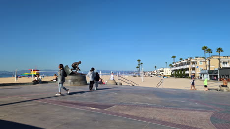 Families-relax-and-explore-on-concrete-slab-with-surfing-monument-at-Manhattan-Beach