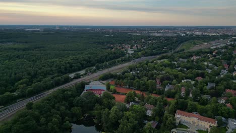 Tennis-stadium-with-red-clay-courts,-surrounded-by-a-lush-green-forest-and-a-small-lake