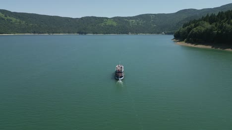 Luftaufnahme-Von-Einem-Boot-Voller-Touristen,-Die-An-Einem-Perfekten-Sommernachmittag-In-Rumänien-Den-Bicaz-See-Hinunterfahren