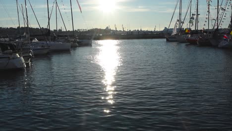 Footage-displays-sunset-at-a-harbor-where-old-yachts,-ships-and-boats-are-docked-and-flags-are-waving-on-them-in-slow-motion-4-K-resolution