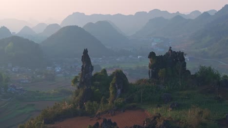 This-drone-footage-captures-a-tranquil-morning-in-Ha-Giang,-North-Vietnam,-revealing-the-lush-rice-fields,-majestic-mountains,-and-a-quaint-town-nestled-behind-the-hills