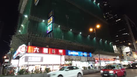 Autobuses-Y-Automóviles-Pasan-Por-Tiendas-Con-Luces-De-Neón-En-El-Distrito-Mong-Kok-De-Hong-Kong-Por-La-Noche