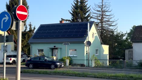 Green-house-with-solar-panels-on-roof-and-parking-car-in-front