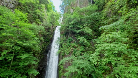 Tall-waterfall-cascading-down-a-rocky-cliff-surrounded-by-lush-green-forest