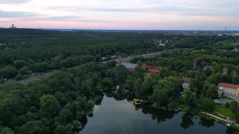 Tennisstadion-Mit-Roten-Sandplätzen,-Umgeben-Von-Einem-üppigen-Grünen-Wald-Und-Einem-Kleinen-See