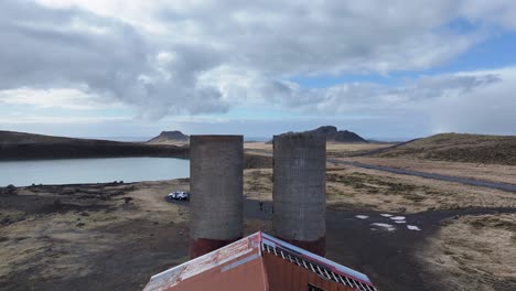 Ein-Drohnenvideo-Zeigt-Eine-Verlassene-Farm-In-Island,-Umgeben-Von-Felsen-Und-Grasland,-Mit-Einem-See-In-Der-Ferne,-Und-Veranschaulicht-Die-Widerstandsfähigkeit-Und-Rückgewinnung-Der-Natur.