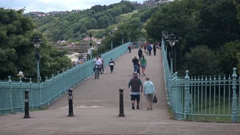 Aufnahmen-Der-Spa-Bridge-In-South-Bay,-Scarborough,-North-Yorkshire-An-Einem-Sommertag-An-Einem-Geschäftigen-Wochenende-Mit-Menschen,-Die-über-Die-Brücke-Laufen