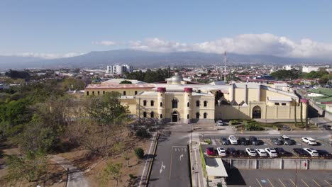 Aerial-view-of-the-Costa-Rican-Center-of-Science-and-Culture-museum,-showcasing-the-building,-parking-area,-and-surrounding-landscape-on-a-sunny-day