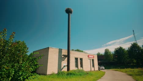 An-empty-stork-bird-nest-perched-atop-a-tall-chimney-adjacent-to-a-Latvian-shop-named-Veikals