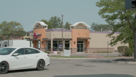 Taco-Bell-restaurant-in-Okemos,-Michigan-with-car-driving-and-stable-video-shot