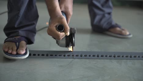 Closeup-of-hands-of-a-South-Asian-man-working-with-an-angle-grinder-to-cut-slotted-angel