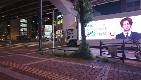 Motion-timelapse-of-people-walking-at-streets-in-Japan-with-cars-around-and-a-highway-bridge-and-neon-lights-of-stores