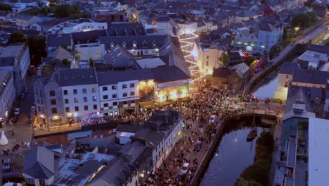 Toma-Aérea-De-Paralaje-Del-Desfile-De-Pegaso-Marchando-Por-El-Centro-De-La-Ciudad-De-Galway-Por-La-Noche.