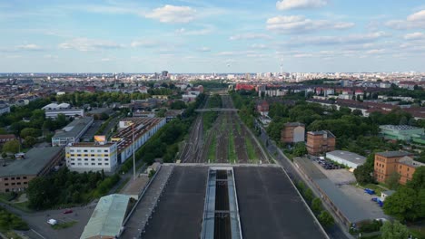 Nice-aerial-view-flight-drone-speed-ramp-hyper-motion-time-lapse-of-modern-train-station-platform-with-glass-roof-in-the-city-Berlin