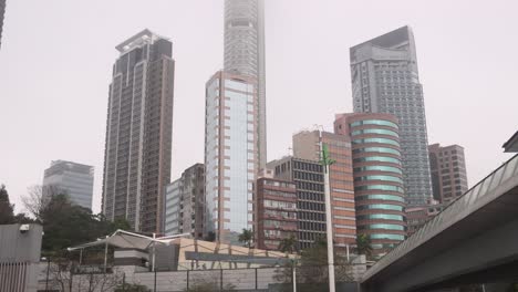 Rascacielos-De-Hong-Kong-Y-Edificios-Altos-Con-El-Horizonte-De-La-Ciudad-Brumoso,-Inclinados-Hacia-Arriba