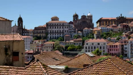 A-view-over-the-roof-tops-with-some-building-and-a-church-on-a-hill-in-the-background,-in-Porto,-Portugal