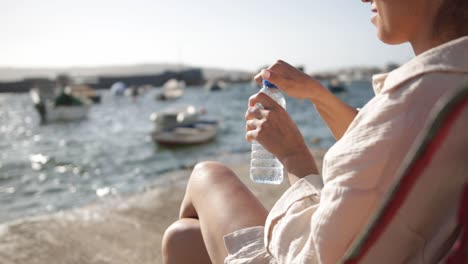 Una-Mujer-Irreconocible-Bebe-Agua-Embotellada-En-La-Explanada-De-La-Bahía-De-San-Pablo-Durante-La-Puesta-De-Sol-En-Malta