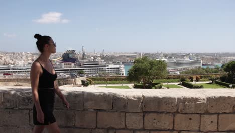 Mujer-Joven-Caminando-Con-Vistas-Al-Puerto-De-Cruceros-De-La-Valeta-En-La-Costa-Mediterránea-De-La-Valeta,-Malta