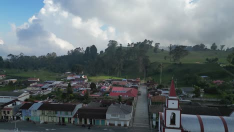 Aerial-rises-over-plaza-and-church-in-mountain-town,-Murillo-COL