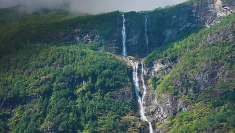 Cascada-De-Dos-Niveles-En-Los-Acantilados-Cubiertos-De-Bosques-Sobre-El-Lago-Loenvatnet