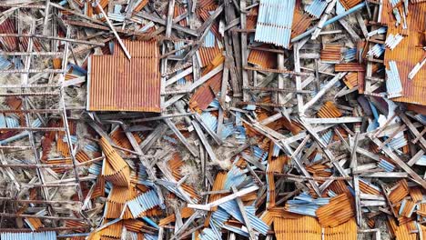 Drone-footage-captures-a-deserted-Iceland-farm,-with-crumbling-structures,-debris,-and-a-lake-in-the-distance,-highlighting-nature's-resilience