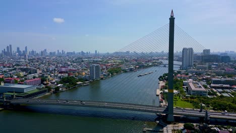 Bangkok,-Tailandia,-Sudeste-Asiático---Vehículos-Cruzando-El-Puente-Rama-Viii-Sobre-El-Río-Chao-Phraya,-Con-El-Paisaje-Urbano-Al-Fondo---Toma-Aérea-De-Drones